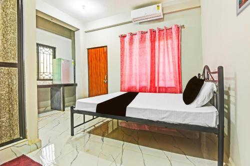 1 dormitorio con 1 cama con cortina roja en Hotel O Pravin Guest House, en Goa