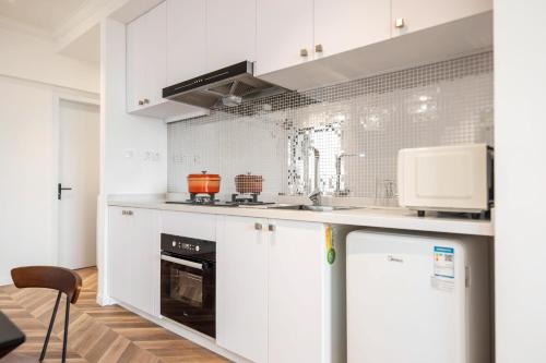 a kitchen with white cabinets and a stove top oven at Shanghai Hills & Serendipity MCM Near Line1 & Line2 People's Square in Shanghai