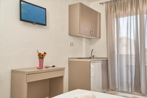 uma cozinha com um lavatório e uma televisão na parede em Studio & Apartments More em Neum