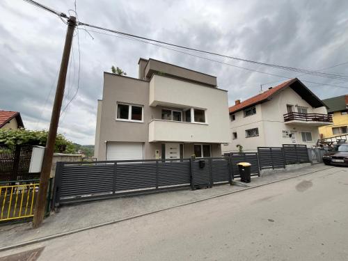 a white house with a fence in front of it at Apartment Mejdan in Tuzla