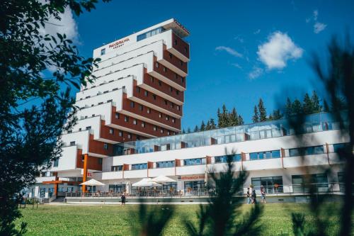 een groot gebouw met mensen die ervoor staan bij Hotel Panorama Resort in Štrbské Pleso