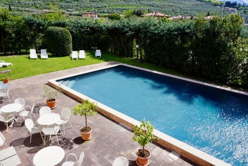 - une piscine avec des tables et des chaises blanches dans l'établissement Hotel Diana, à Riva del Garda