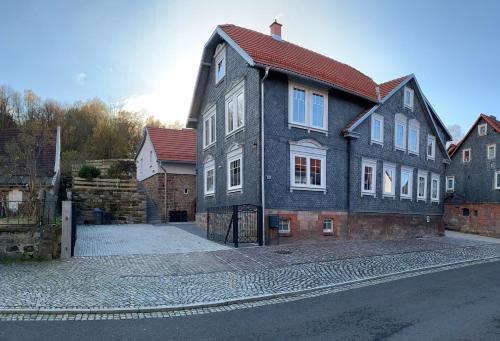 uma casa grande com um telhado vermelho numa rua em Ferienwohnung - Zum alten Fritz - Suhl, 2 Schlafzimmer, 2 Terrassen em Suhl