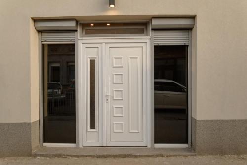 une porte blanche d'un bâtiment avec une voiture à l'intérieur dans l'établissement Sen's Studio, à Leskovac