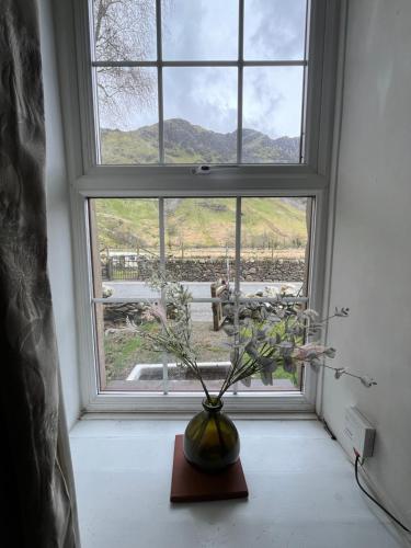 een vaas op een tafel voor een raam bij Terfyn Cottage in Dinorwic