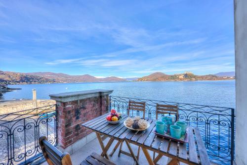 einen Tisch und Stühle auf einem Balkon mit Blick auf das Wasser in der Unterkunft Aparthotel Arona - Happy Rentals in Arona