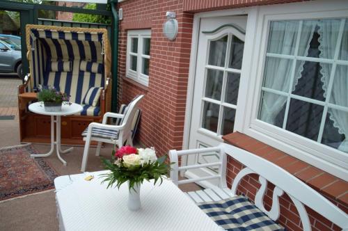 une terrasse couverte avec une table et un vase de fleurs dans l'établissement Nordseestübchen Whg 03, à Nieblum