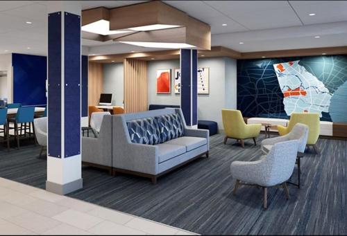 een lobby met een bank, stoelen en tafels bij Holiday Inn Express & Suites Austin Airport East, an IHG Hotel in Austin