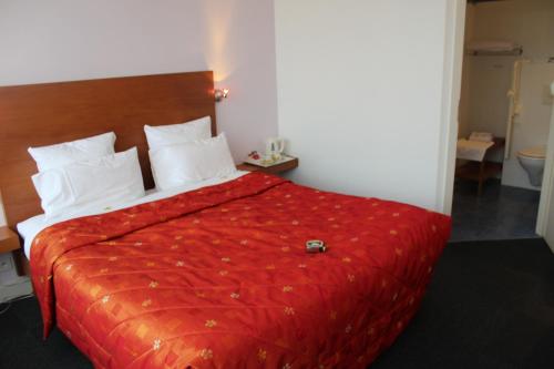 Cette chambre d'hôtel dispose d'un lit avec un couvre-lit rouge. dans l'établissement Hôtel Restaurant Logis La Palette, à Wettolsheim