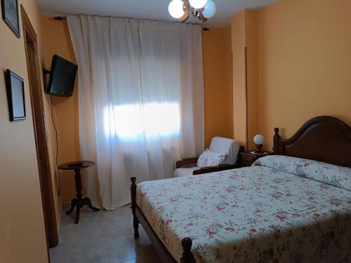 um quarto com uma cama, uma cadeira e uma janela em PENSIÓN* AS VIÑAS em Puebla del Brollón