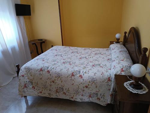 um quarto com uma cama com colcha floral em PENSIÓN* AS VIÑAS em Puebla del Brollón