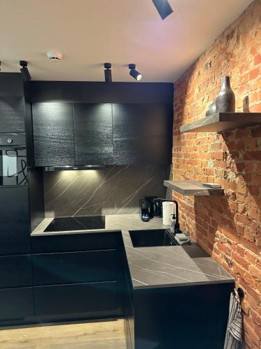 a kitchen with black cabinets and a brick wall at Luxury Apartment with Cosy Garden! in Ghent