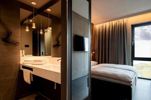 een badkamer met een wastafel, een bed en een spiegel bij Zleep Hotel Zürich-Kloten in Kloten