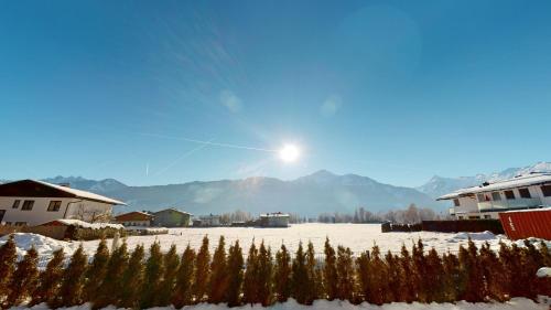 een met sneeuw bedekt veld met bomen en de zon bij Kitzview Idyll in Zell am See