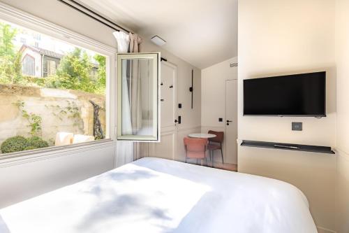 1 dormitorio con ventana grande y TV en Maison du Moulin Vert, en París