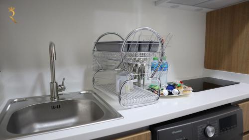 um lavatório de cozinha com um suporte para secar pratos ao lado de um lavatório em Valentina Studio Transit Apartment in Masdar City em Abu Dhabi