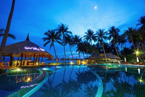 uma piscina à noite com palmeiras em Muong Thanh Holiday Muine Hotel em Mui Ne