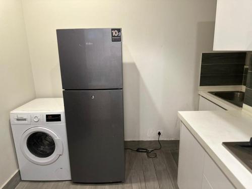 a kitchen with a refrigerator next to a washing machine at The Opus Luxury Residences in Lahore