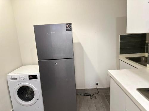 a kitchen with a refrigerator and a washing machine at The Opus Luxury Residences in Lahore