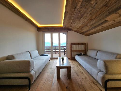 a living room with two couches and a table at Magnifique attique avec vue sur le lac de la Moubra in Crans-Montana