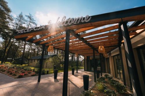 un bâtiment avec une pergola en bois devant lui dans l'établissement Folga Resort, à Mrzeżyno