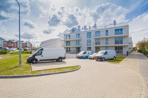 dos furgonetas estacionadas en un estacionamiento frente a un edificio en Apartament Terenia, en Puck