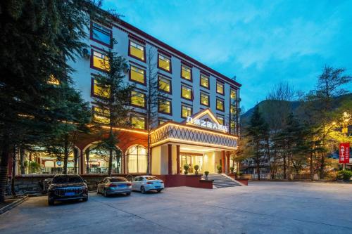 un hôtel avec des voitures garées devant lui dans l'établissement Jiuzhai Journey Hotel, à Jiuzhaigou