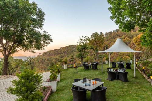 eine Terrasse mit Tischen und Stühlen und einem weißen Sonnenschirm in der Unterkunft Alaya Stays Live Life 2BHK Apartment in Kasauli in Kasauli