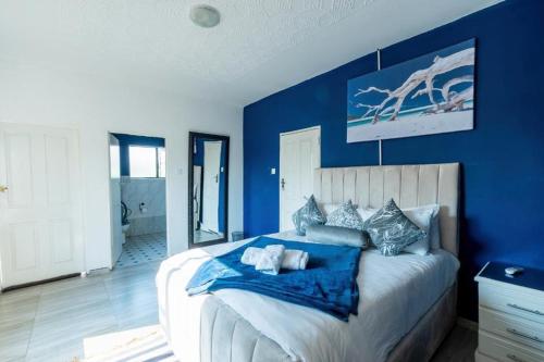 een slaapkamer met blauwe muren en een groot bed bij The Crescent Victoria Falls in Victoria Falls