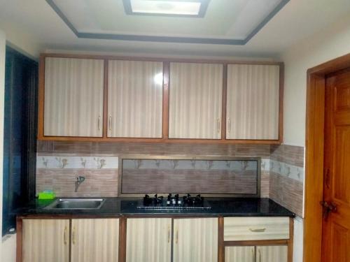 a kitchen with wooden cabinets and a sink at Ilyasin Guest House in Skardu