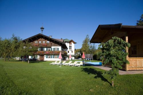 un hôtel avec une pelouse dotée de chaises longues et une piscine dans l'établissement Hotel Gasthof Obermair, à Fieberbrunn