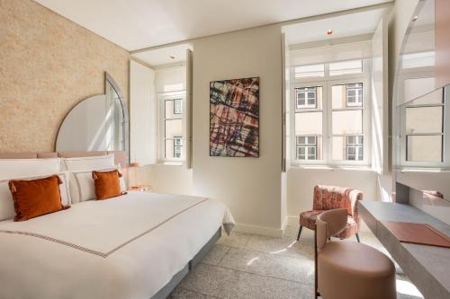 een slaapkamer met een bed, een stoel en ramen bij Convent Square Lisbon, Vignette Collection by IHG in Lissabon