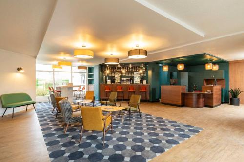 een restaurant met tafels en stoelen en een bar bij Le Carline, Sure Hotel Collection by Best Western in Caen