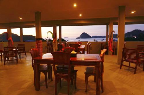 restauracja ze stołami i krzesłami oraz widokiem na ocean w obiekcie Komodo Lodge w Labuan Bajo