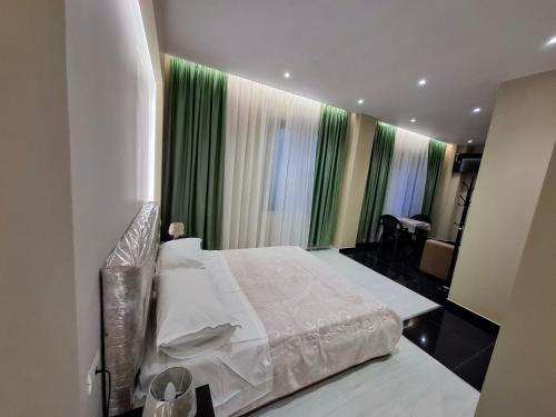 a bedroom with a large bed and green curtains at CityCenterHotel Shkoder in Shkodër