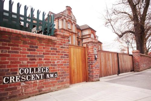 a brick house with a wooden gate and a fence at Palmers Lodge Swiss Cottage in London