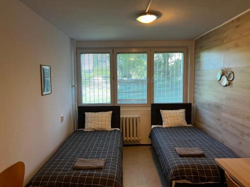 two beds in a room with two windows at Warszawa Zachodnia in Warsaw