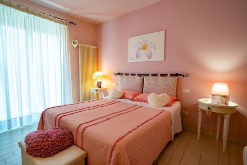 Un dormitorio con una cama con paredes rosas y una ventana en Petali Rosa, en Polignano a Mare