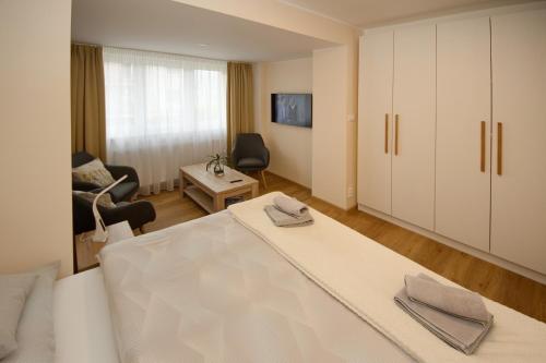 a white bedroom with a bed and a chair at Apartmán nad Ottovkou in Luhačovice