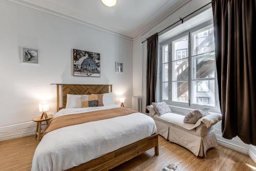 ein Schlafzimmer mit einem großen Bett und einem Fenster in der Unterkunft North House - Hôtel Automatisé Manoir des Remparts in Québec