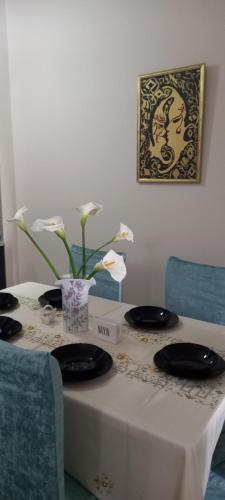 a table with two plates and a vase with flowers on it at Panoramic apartment in Shkodër