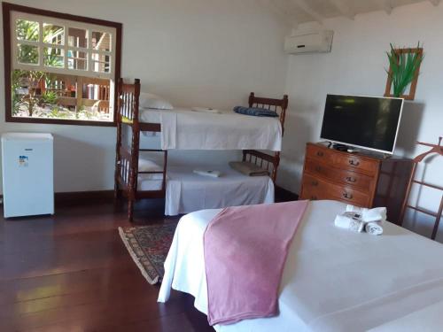 a hotel room with two beds and a television at Pousada Éden in Angra dos Reis