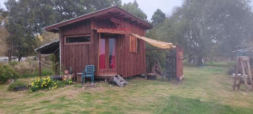 een kleine houten schuur met een stoel in een tuin bij Chacrita Aguaribay in Villa Argentina