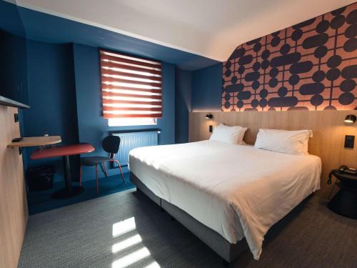 um quarto com uma cama grande e paredes azuis em Ibis Styles Charleroi Airport Aero 44 em Charleroi