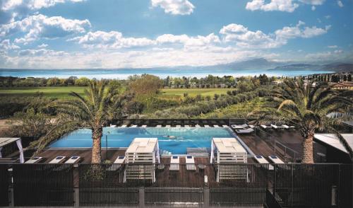 uma piscina com cadeiras e palmeiras em Quellenhof Luxury Resort Lazise em Lazise