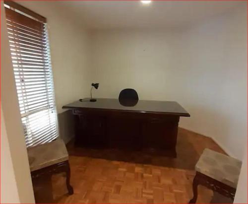 a desk in the corner of a room with a window at A Unique Holiday Home between Avalon Airport and Melbourne CBD in Werribee