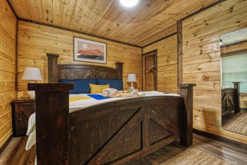 een slaapkamer met een bed in een houten hut bij Adventure Retreat/Cabin/Pool+Hot Tub/Game Room+Theater in Sevierville