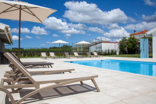 uma piscina com espreguiçadeiras e um guarda-sol em NR Suites na Mealhada