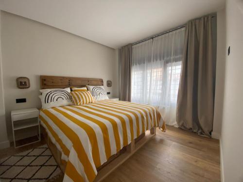 een slaapkamer met een gestreept bed en een raam bij Cornelia Suites 01 in Santander