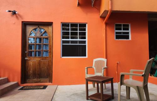 una casa naranja con dos sillas y una puerta en Saloma's ZionGates, en Castries